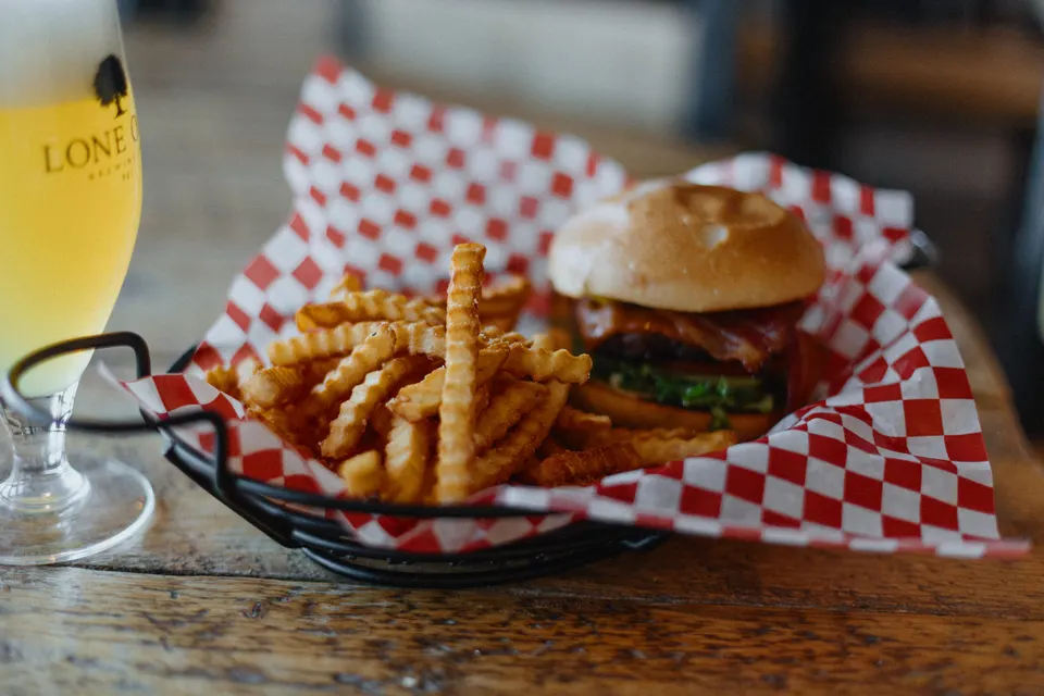 Burger and seasoned fries with a glass of Lone Oak beer