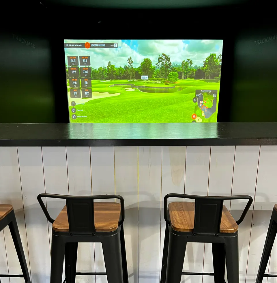 Bar stools facing the golf simulator screen at Lone Oak