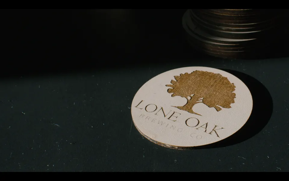 Lone Oak coaster with a gold oak tree on a dark bar top